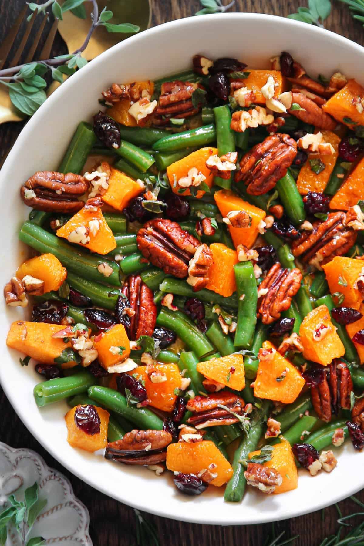 Healthy Green Beans With Butternut Squash, Pecans, and Cranberries in a white bowl.