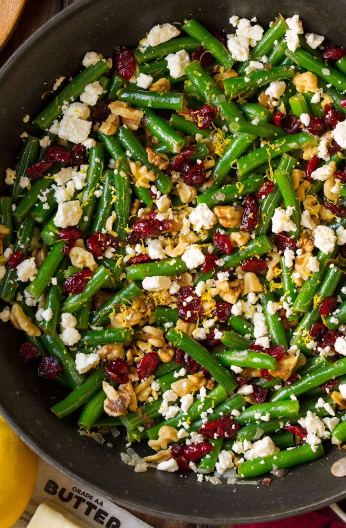 Yummy Lemon Butter Green Beans With Cranberries, Walnuts, and Feta in a  black bowl.