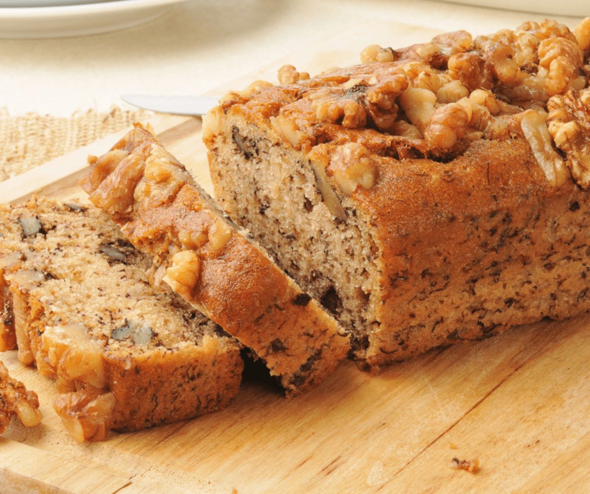 Partially sliced Moist Banana Bread on a wooden cutting board.