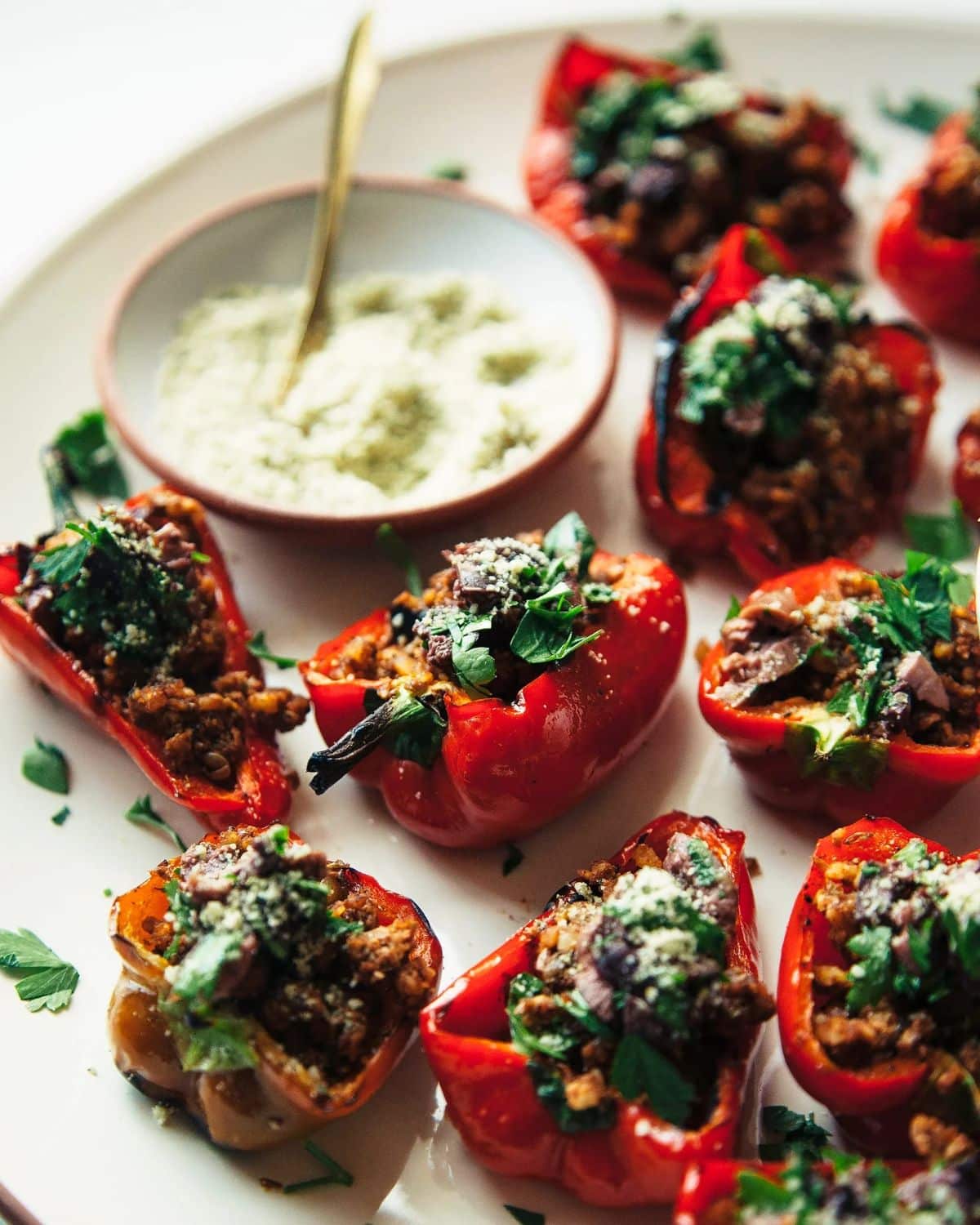 Flavorful Grilled Mini Peppers with Spiced Walnut and Lentil Crumble on a white tray with a bowl of dip.