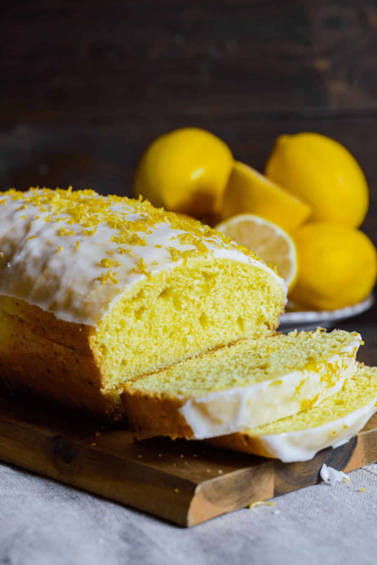 Partially sliced Lemon Loaf on a wooden cutting board.