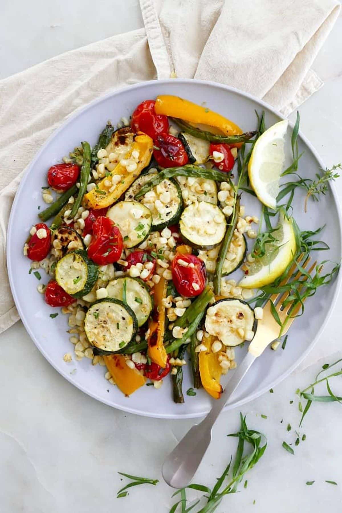 Yummy Tarragon Roasted Summer Vegetables on a white plate with a fork.