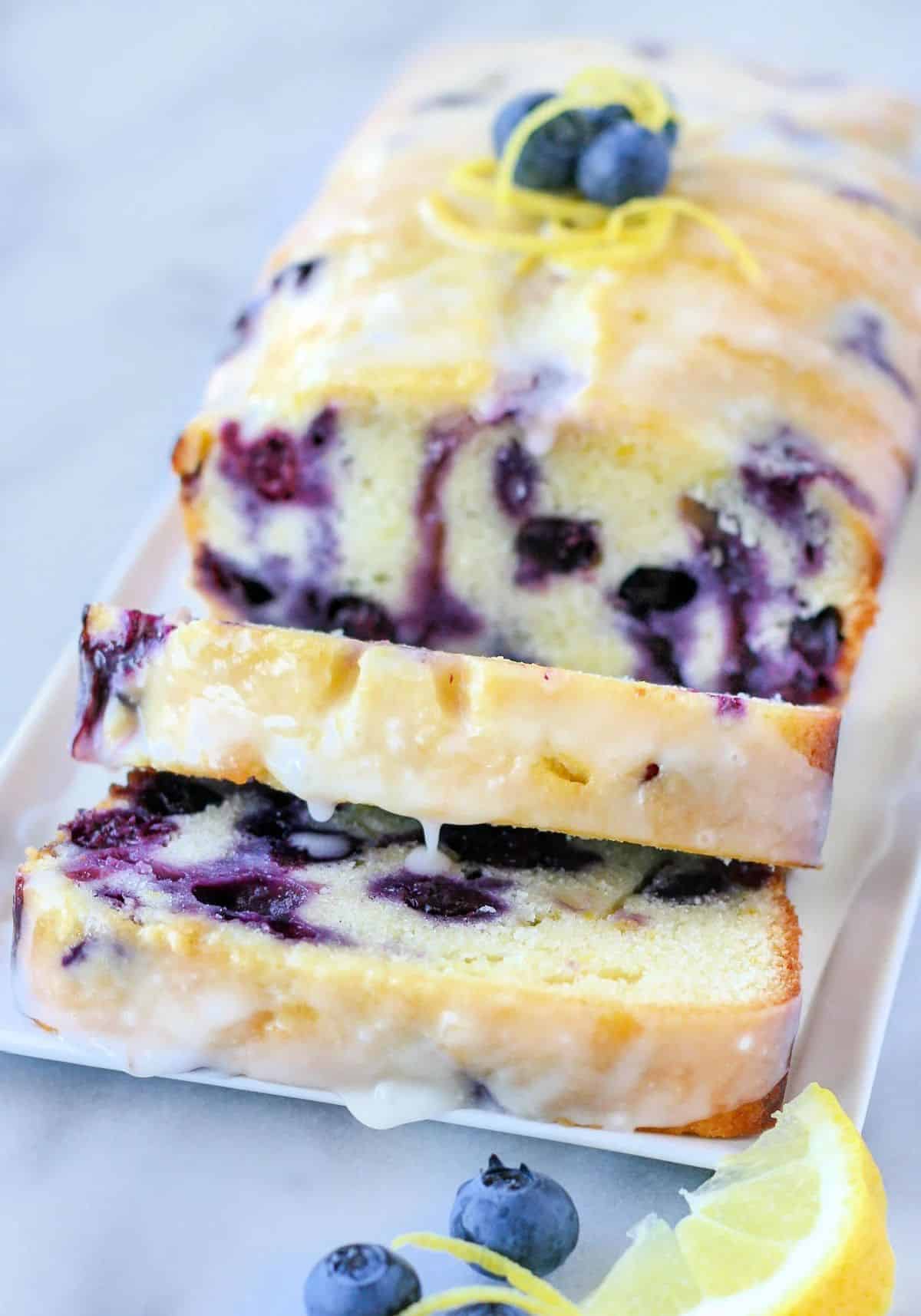 Partially sliced Lemon Blueberry Bread on a white tray.