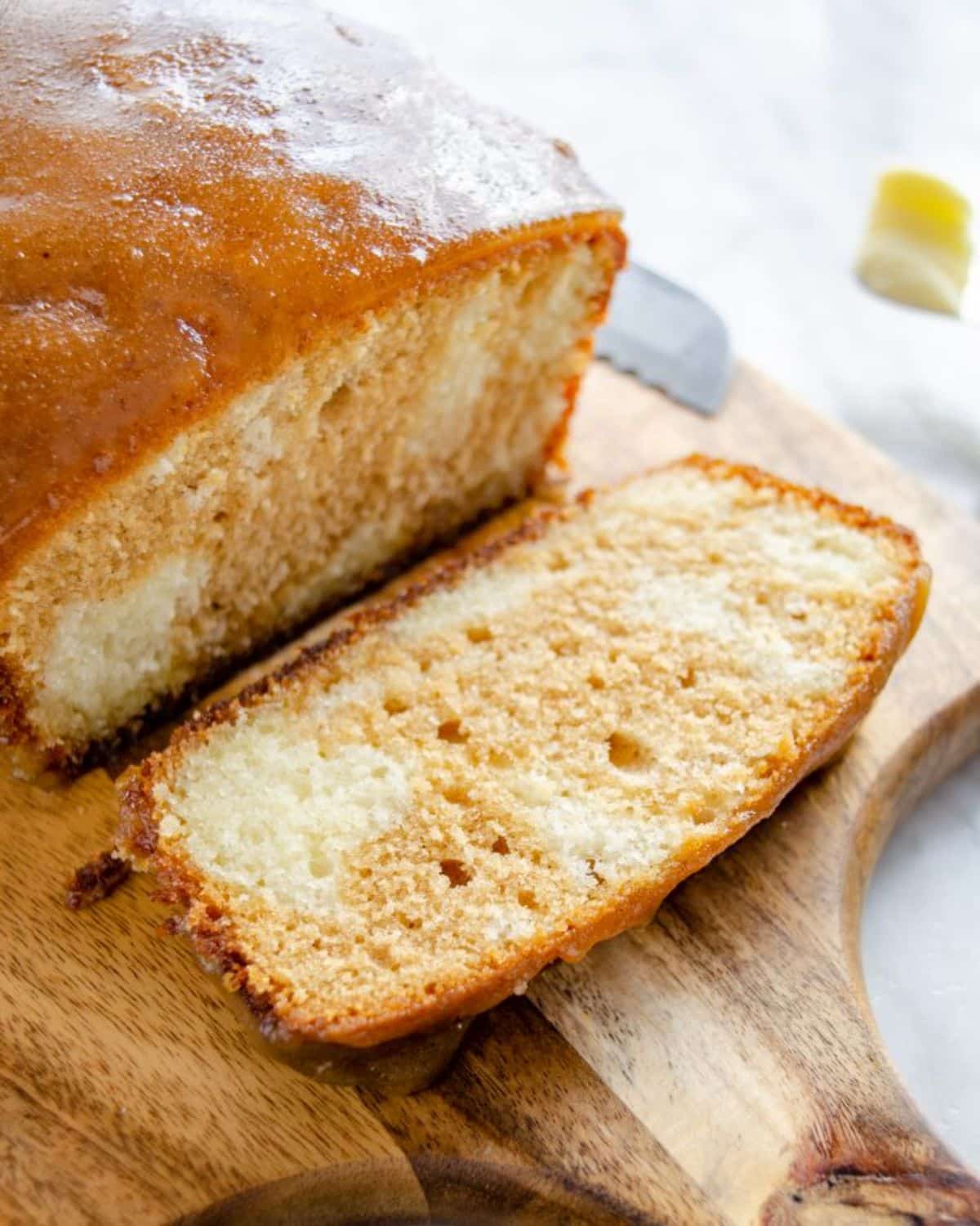 Partially sliced Cinnamon Sugar Donut Sweet Bread on a wooden cutting board.