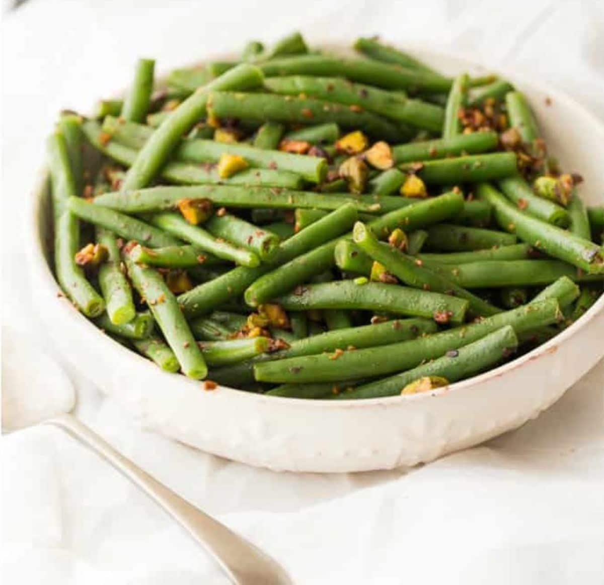 Tasty Green Beans With Warm Pistachio Vinaigrette in a white bowl.