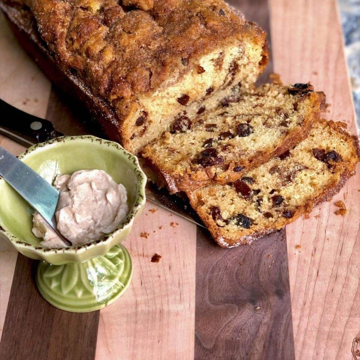 Partially sliced Buttery Cinnamon Raisin Bread on a wooden tray.