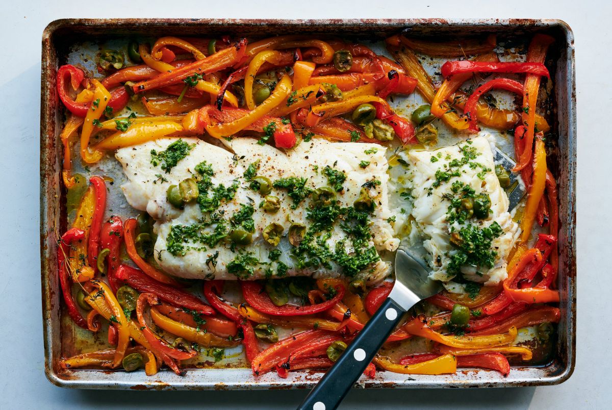 Scrumptious Sheet Pan Roasted Fish with Sweet Peppers with a spatula.