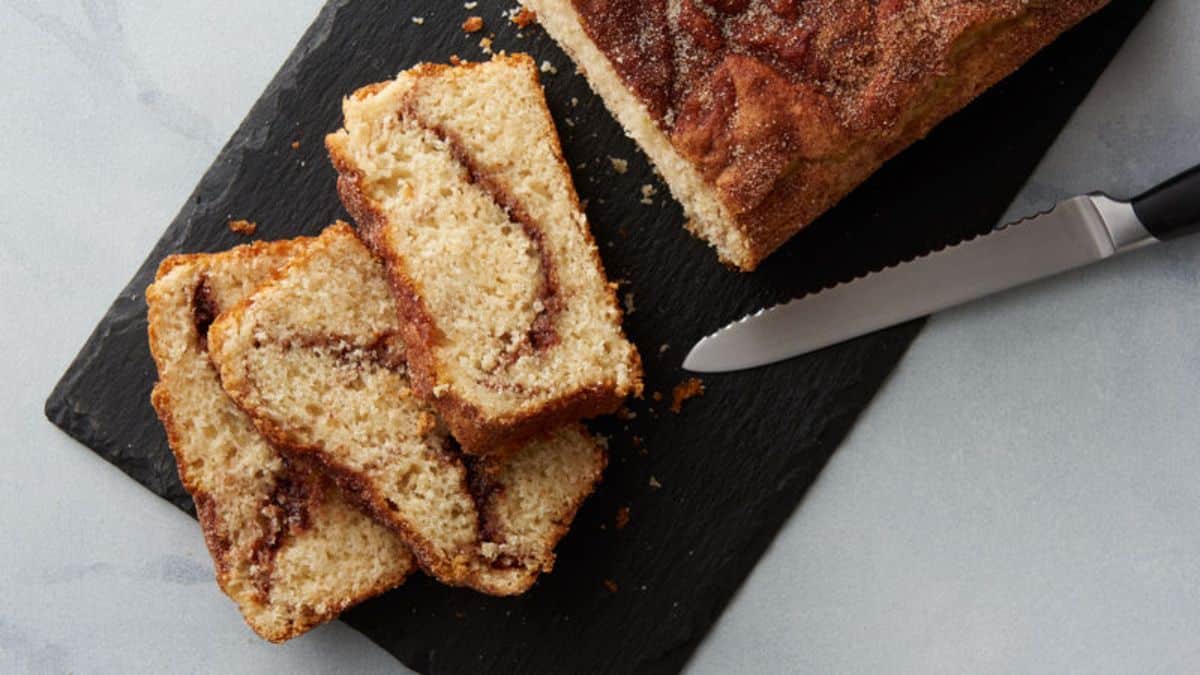 Partially Cinnamon Sugar Quick Bread on a wooden cutting board.