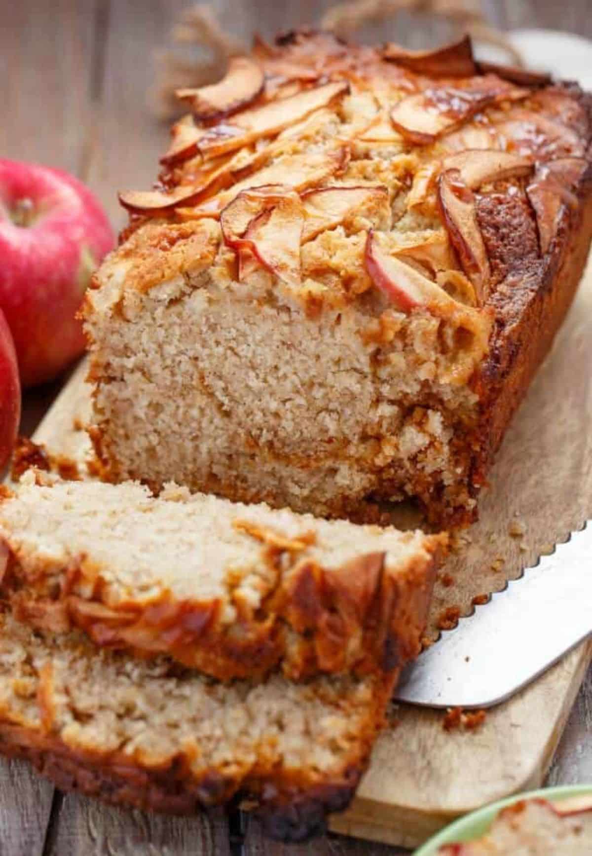 Partially sliced Apple Cinnamon Bread with Caramel on a wooden cutting board.