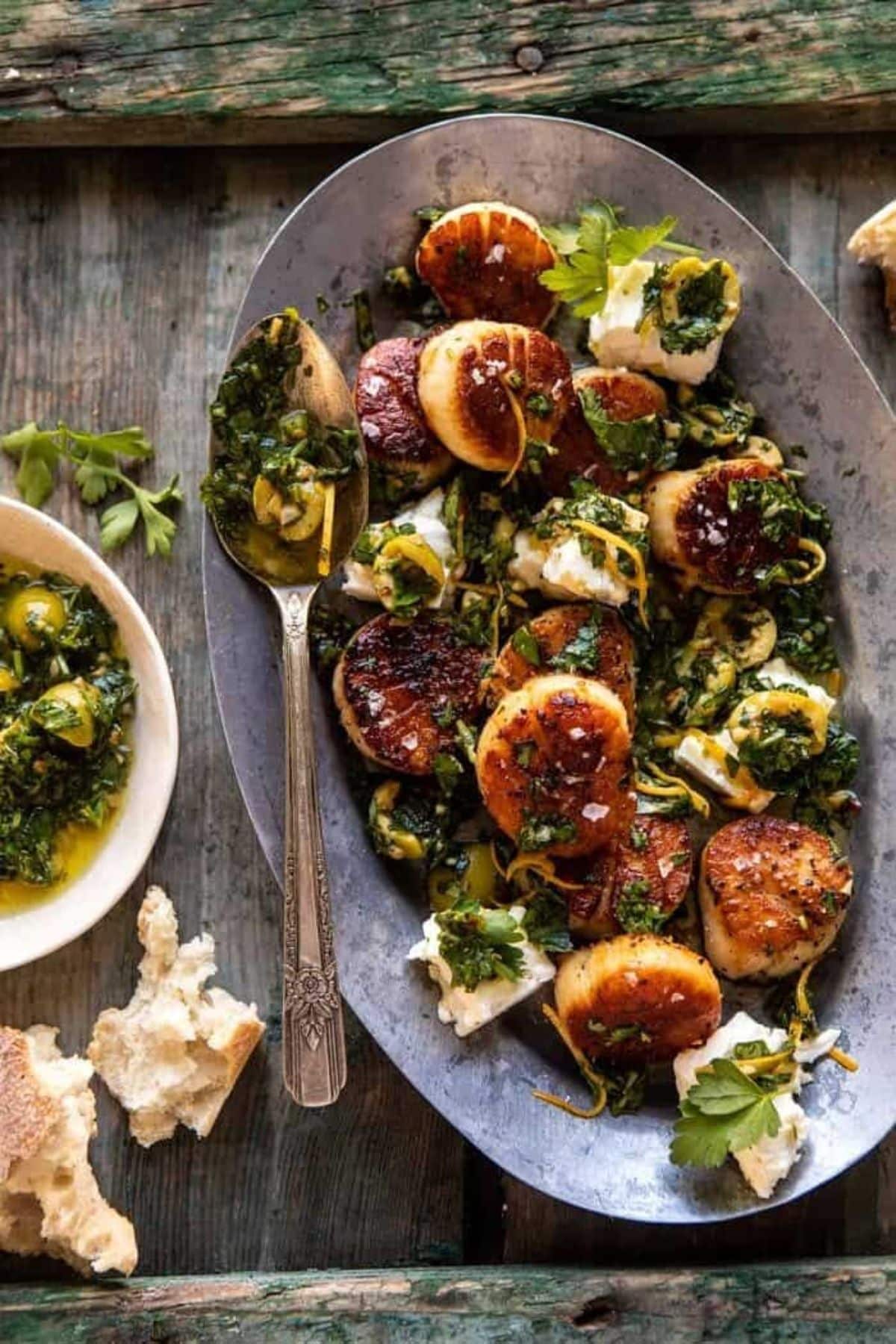 Flavorful Herbed Garlic Butter Scallops with lemony Feta Dressing on a metal tray with a spoon.