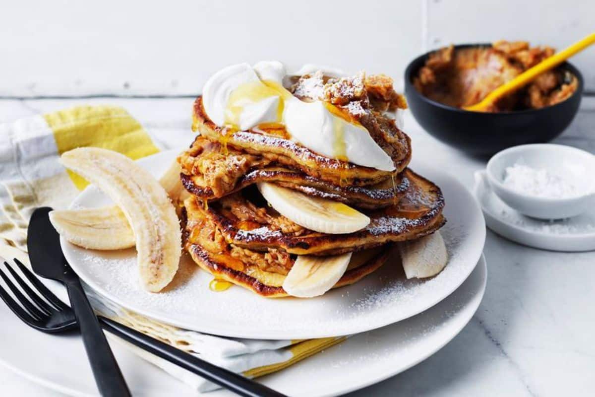 A pile of Ricotta Pancakes with Honeycomb Butter on a white plate.