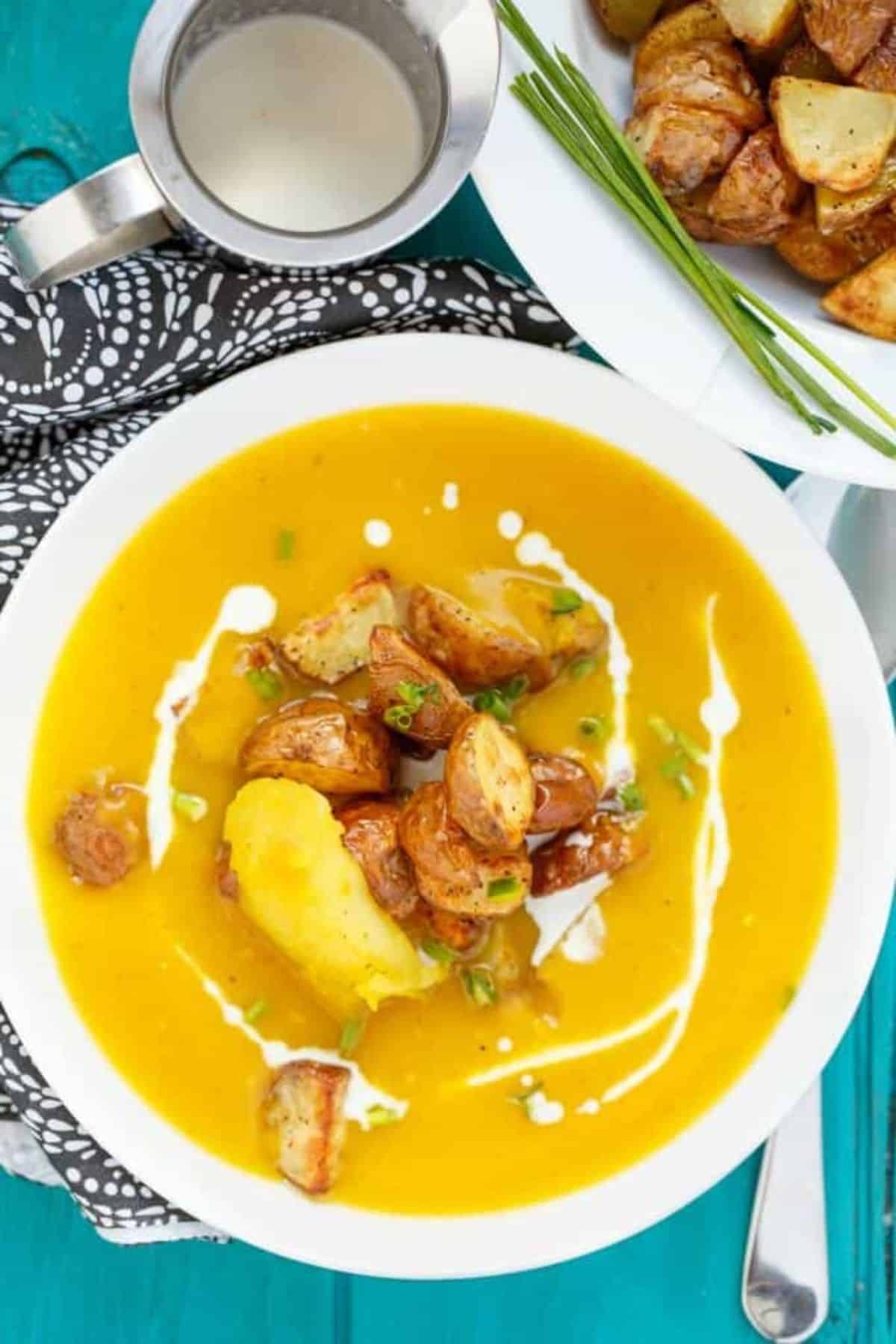 Creamy Roasted Apple Pumpkin Soup with Potatoes on a white plate.