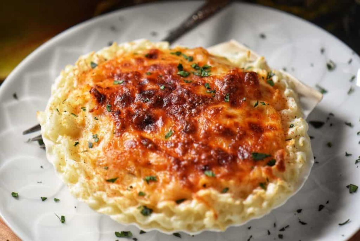 Crunchy Coquille St. Jacques on a white plate with a fork.