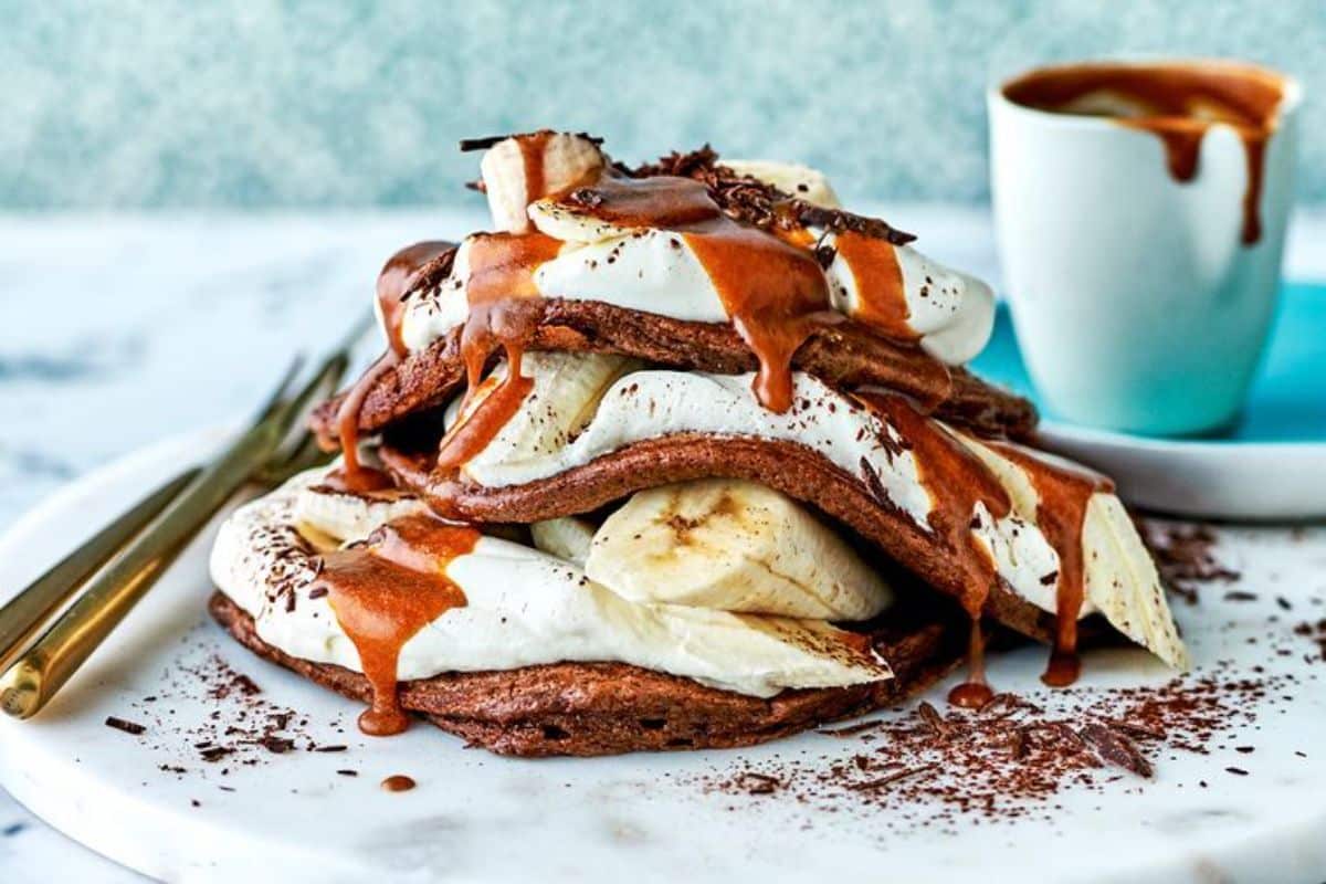 A pile of Choc Banoffee Pancakes on a white tray.