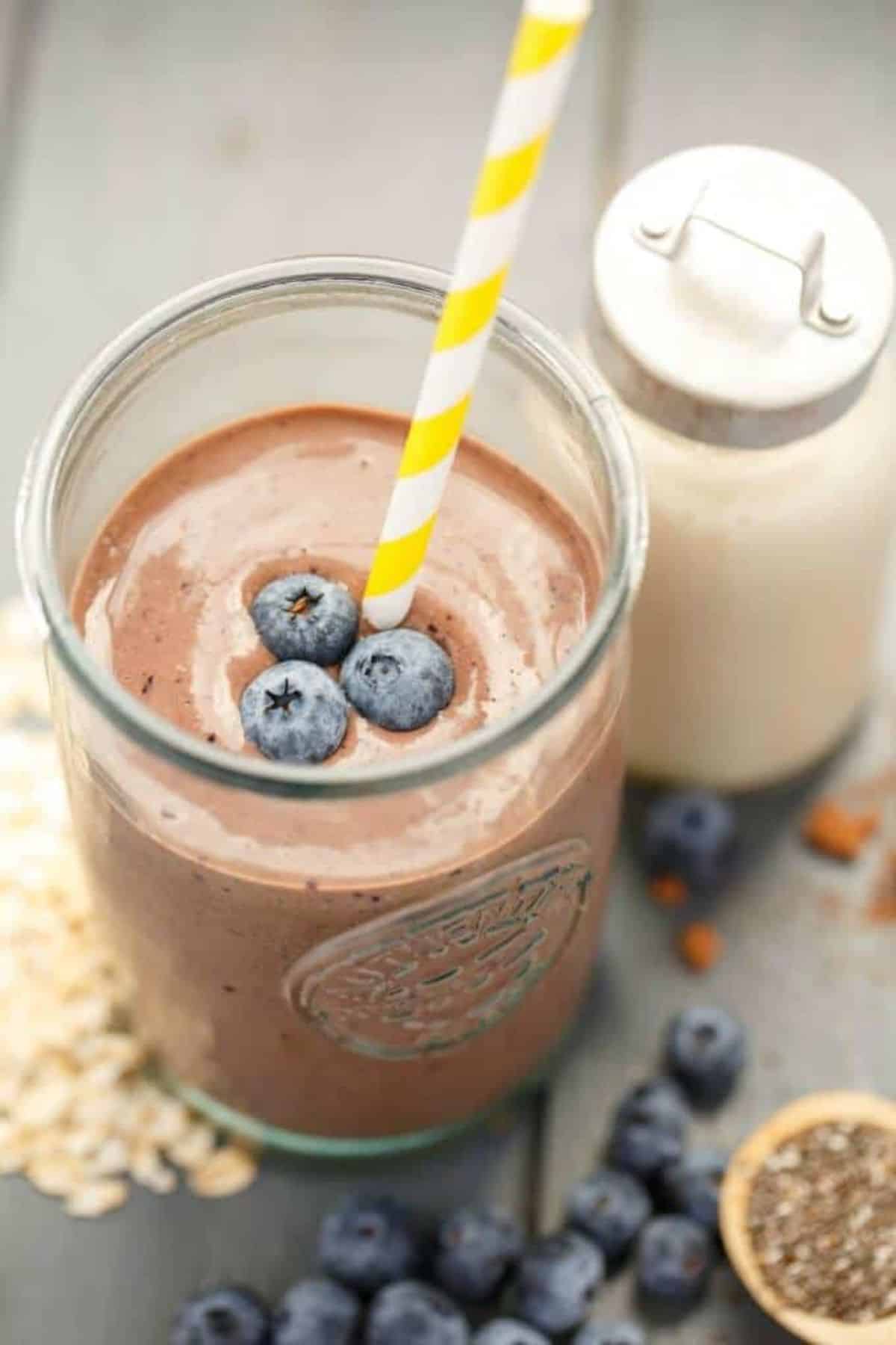 Creamy Almond Milk Banana Blueberry Breakfast Smoothie in a glass jar with a straw,