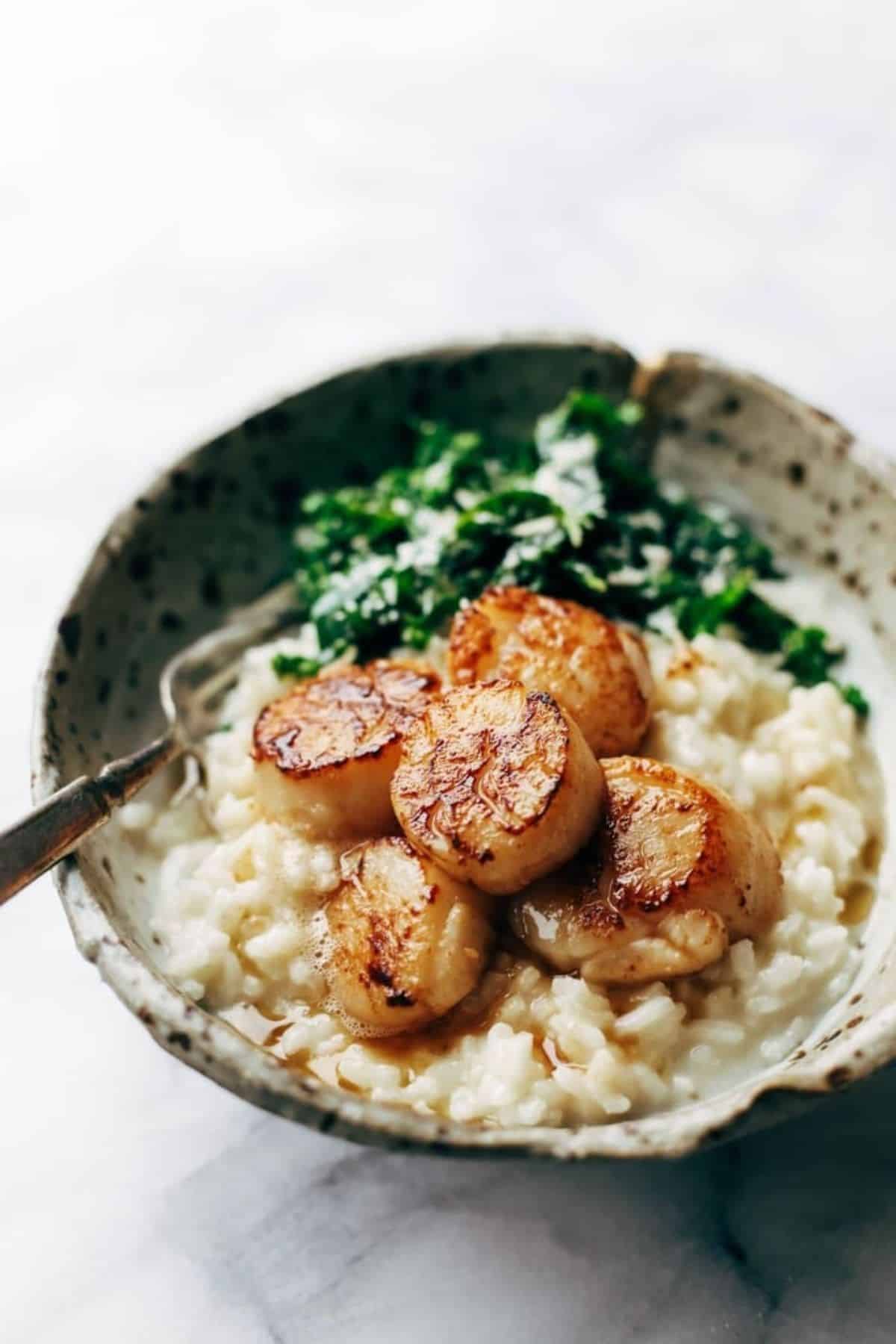Flavorful Brown Butter Scallops with Parmesan Risotto in a bowl with a fork.