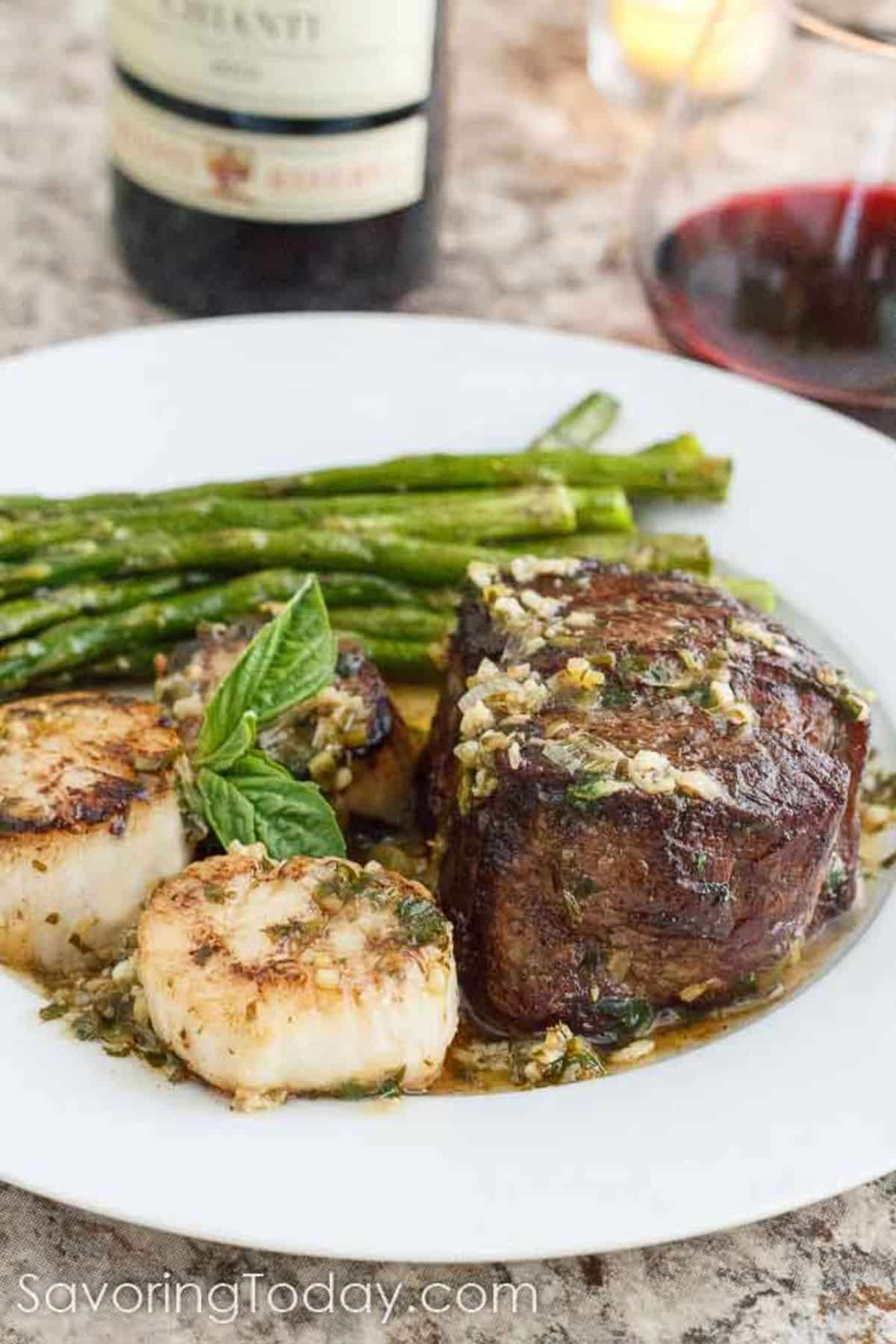 Delicious Scampi-Style Steak and Scallops with asparagus on a white plate.