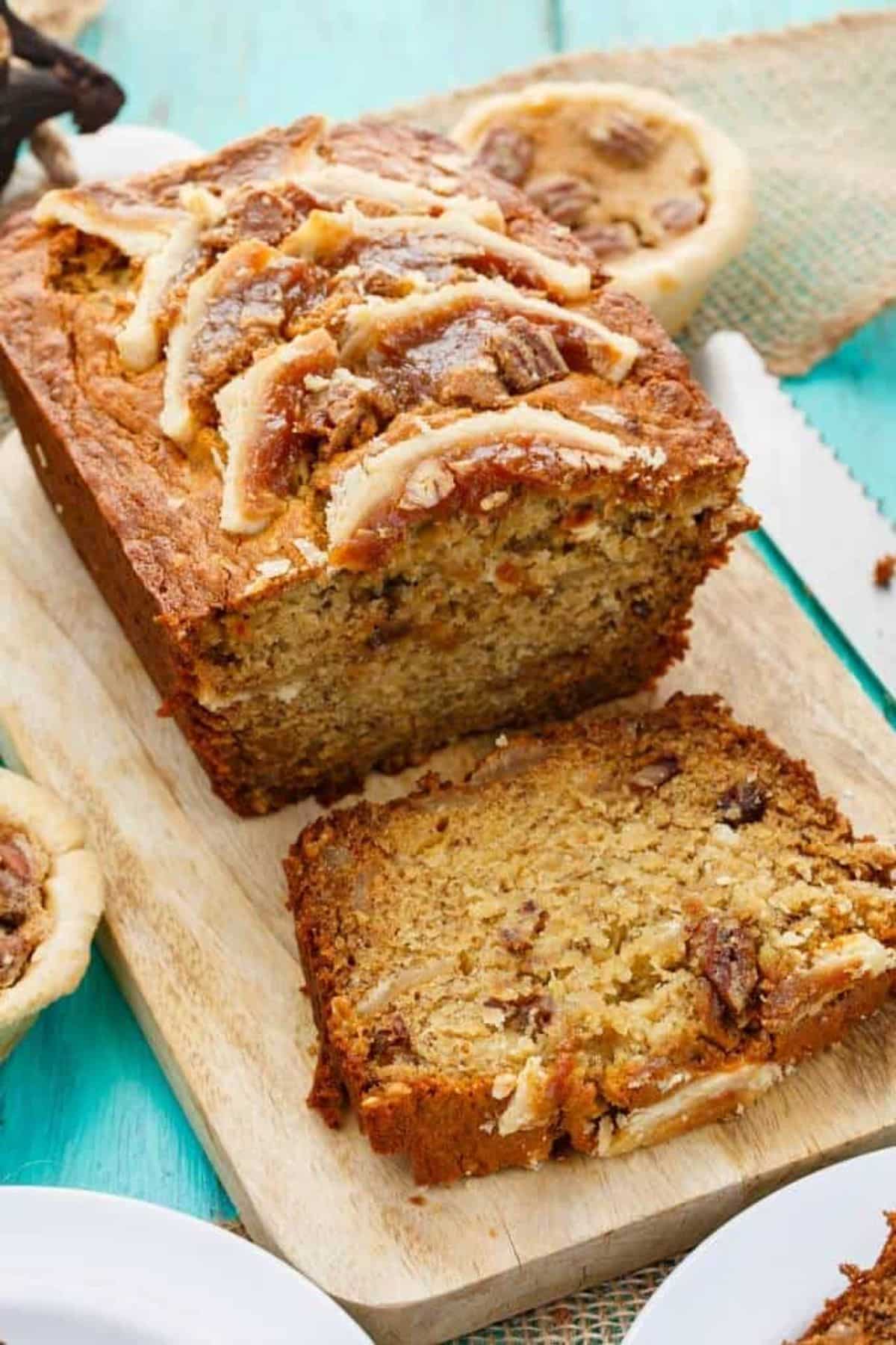 Partially sliced Homemade Butter Tart Banana Bread on a wooden cutting board.